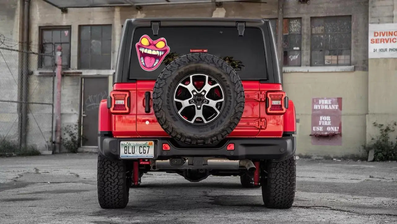 Here are a few options for alt text, keeping under 100 characters:

* **Jeep with monster face sticker on spare tire.**
* **G
