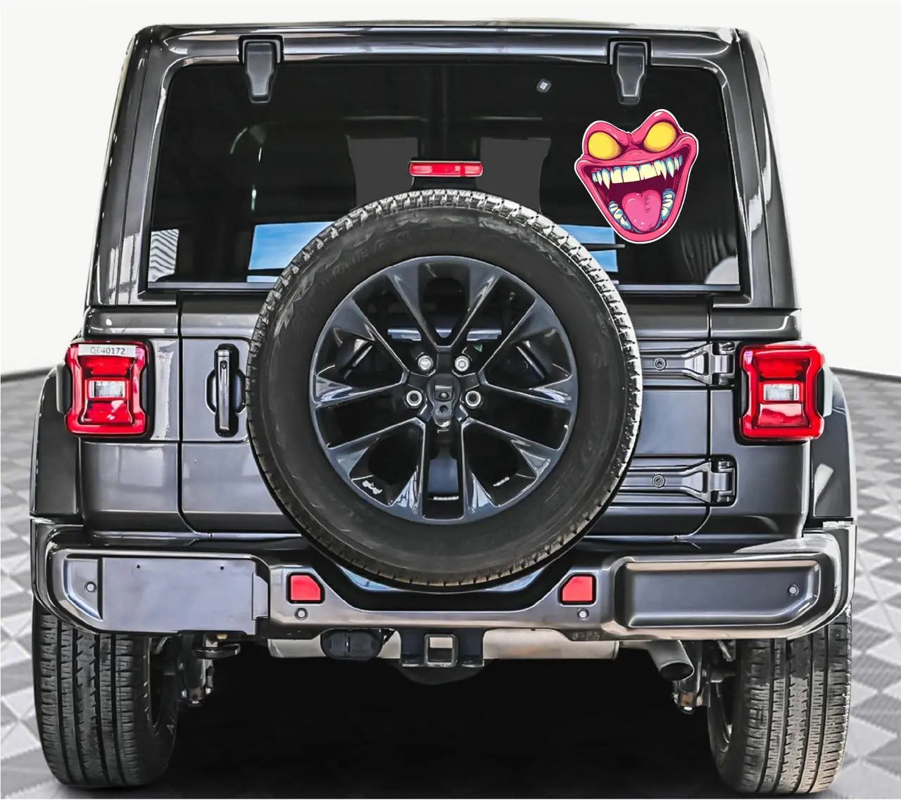 Here are a few options for alt text, keeping under 100 characters:

* **Jeep with monster face sticker on spare tire.**
* **G