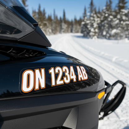 Snowmobile registration number decals applied to black snowmobile cowling on Ontario winter trail