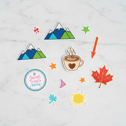 Custom die-cut vinyl stickers flat lay on marble - mountains, maple leaf, coffee cup, brand logos
