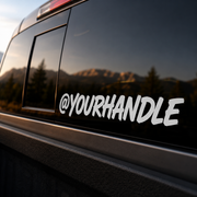 Custom white social handle decal on a dark pickup truck rear window